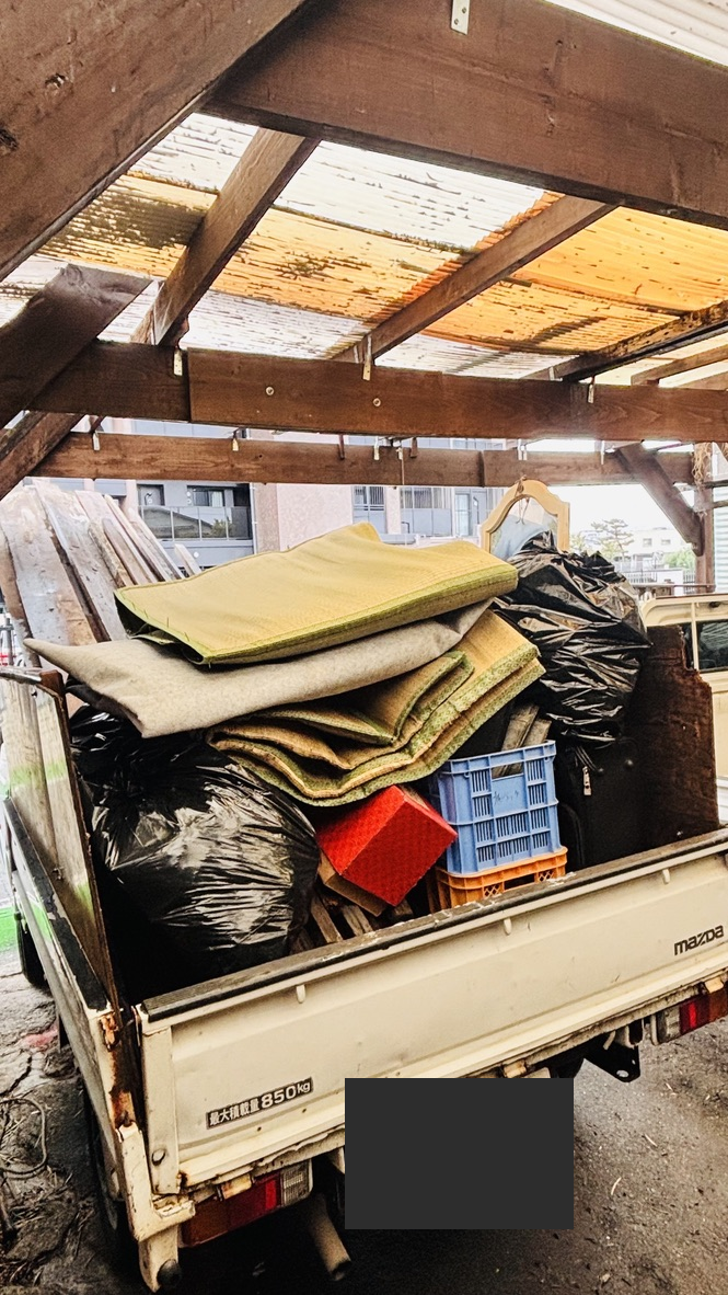 トラックの荷台に寝具や袋などを積んだ様子
